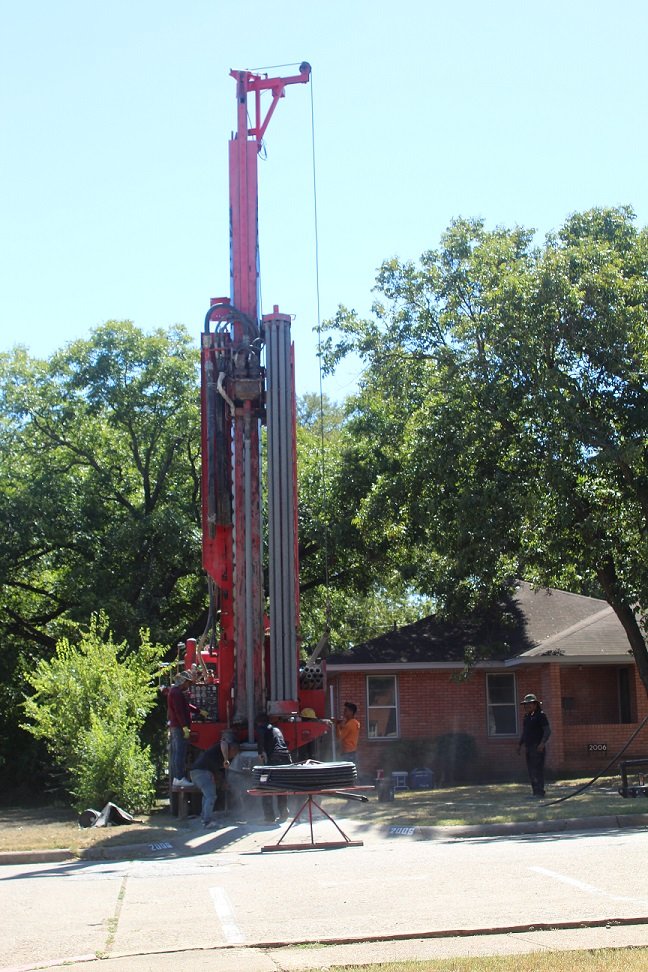 The drilling rig's mast raised over the backyard of the 1954 Dallas home during well drilling