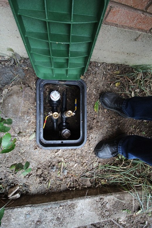 Geothermal loop valve box set into the ground beside the home's foundation