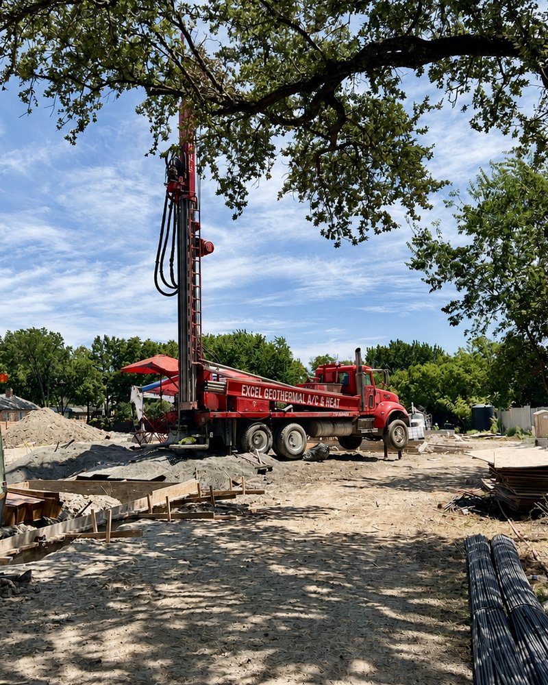 Excel Geothermal drilling rig boring vertical wells on a residential lot beneath mature oak trees